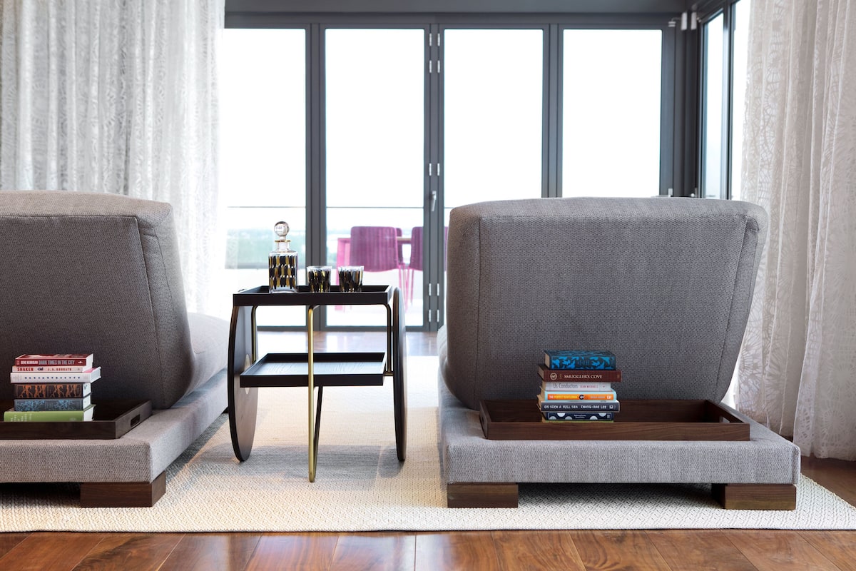 A modern living room with two grey sofas, a small wooden coffee table, and a stack of books.