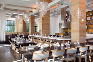 A restaurant with multiple dining tables, chairs, and hanging crystal chandeliers.
