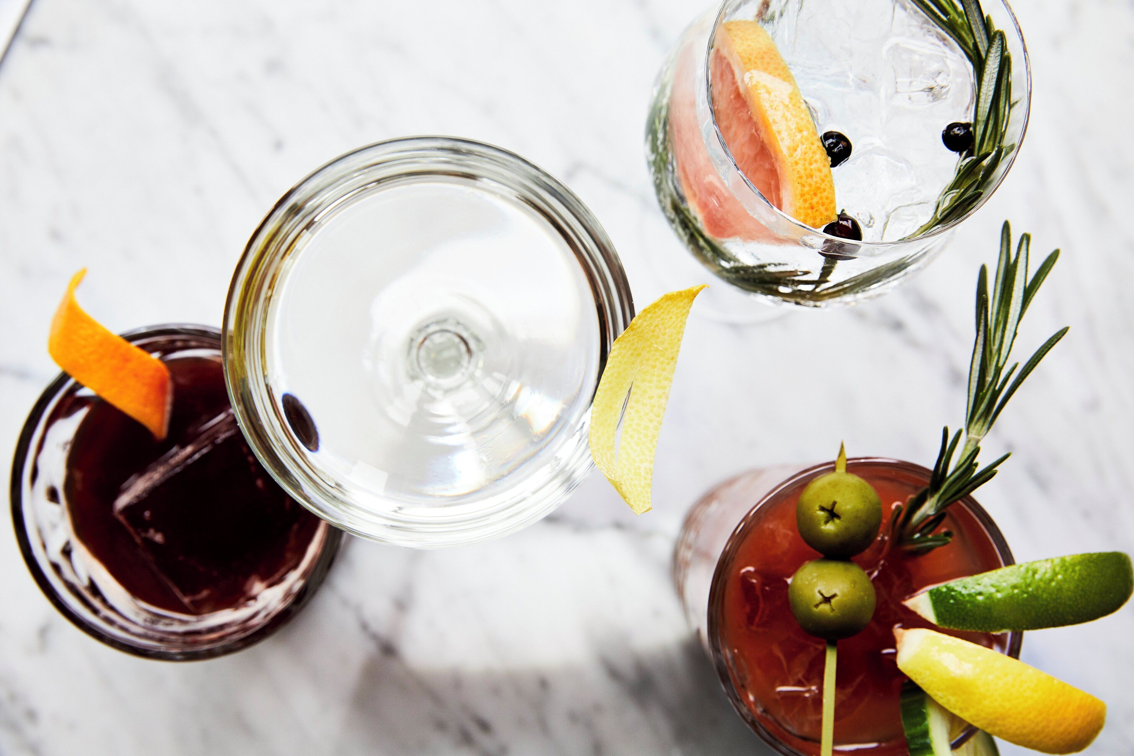 Three different cocktails with garnishes on a marble surface.