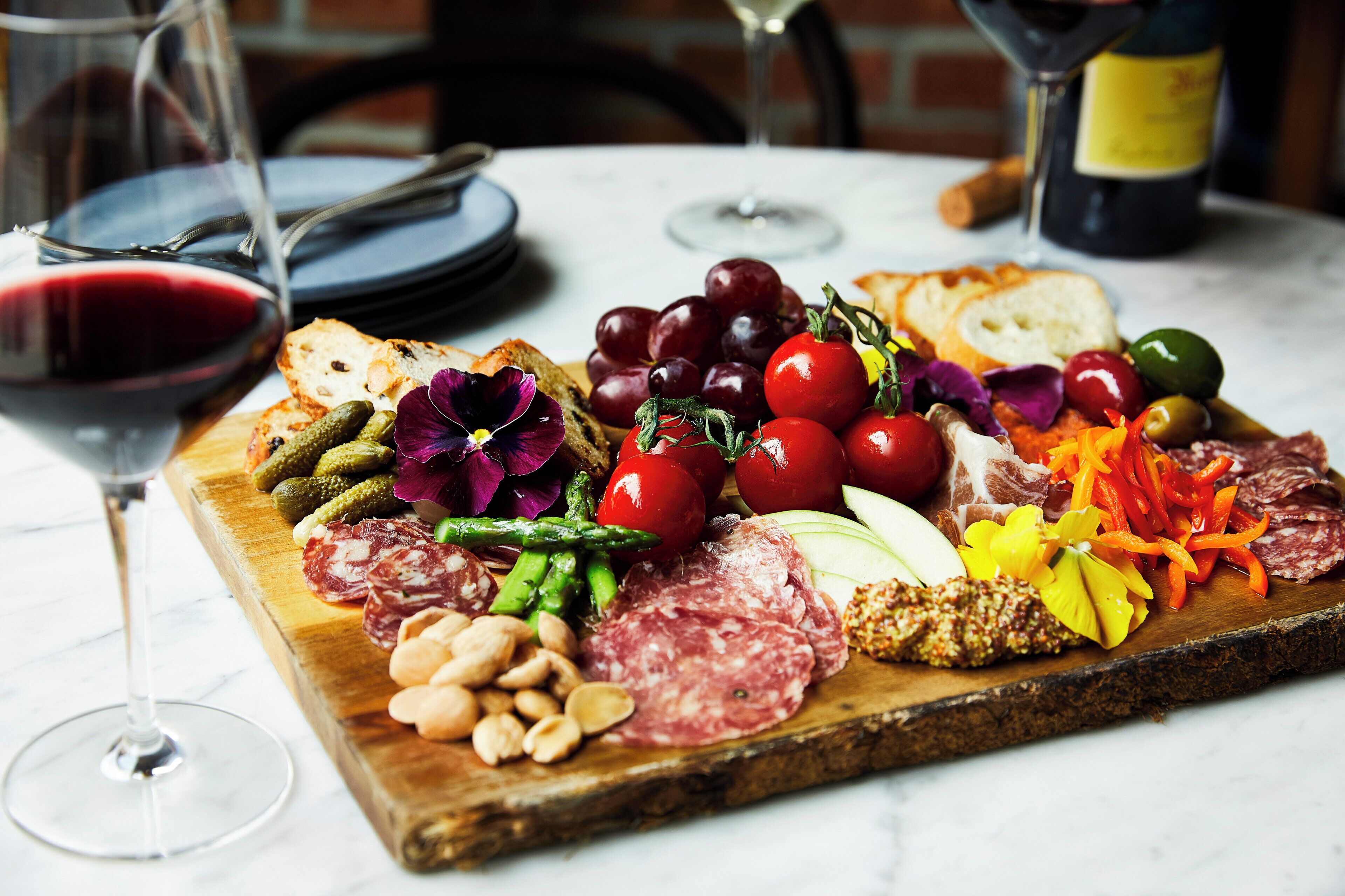 A charcuterie board with various meats, cheeses, and vegetables on a wooden board.