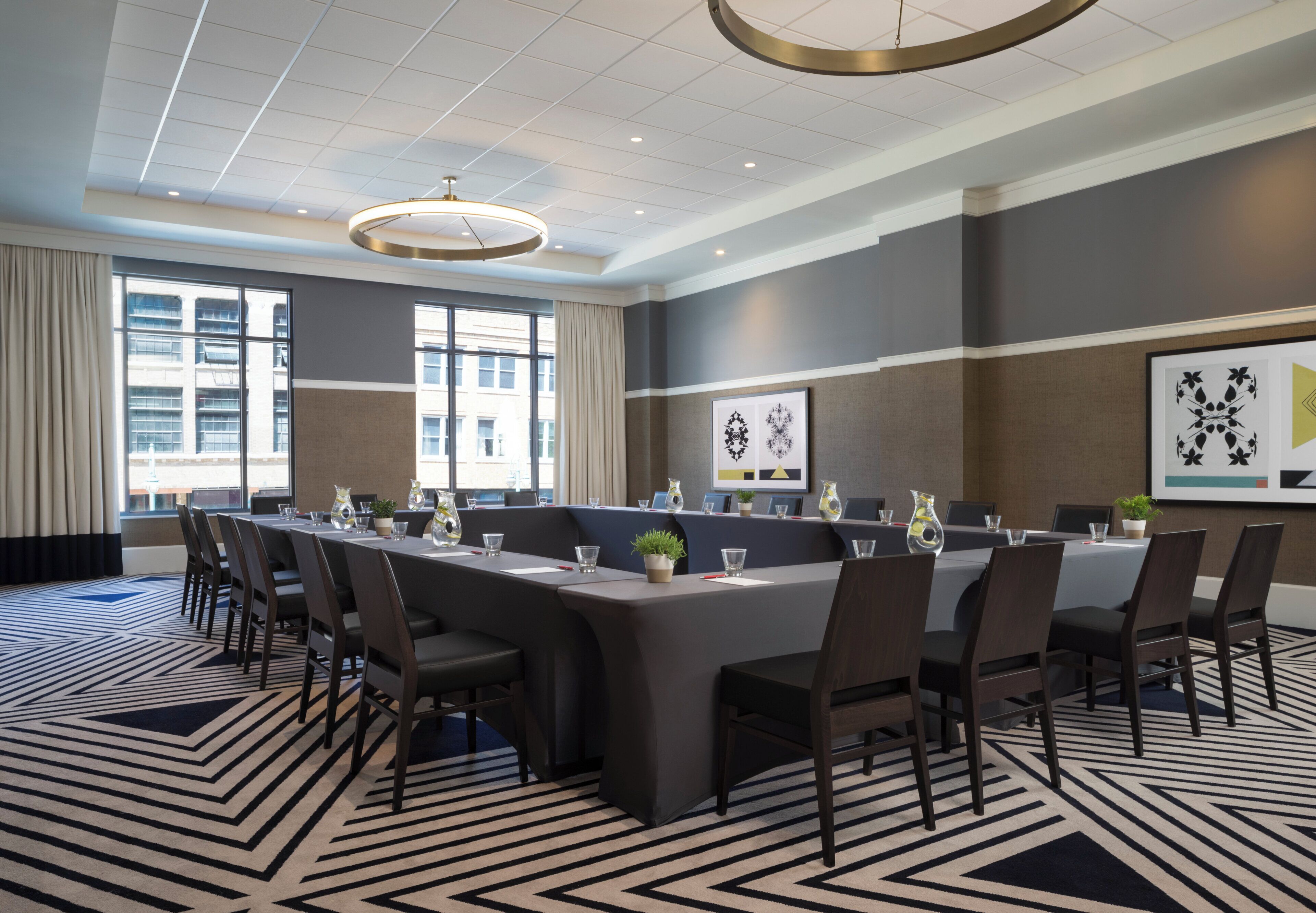 A conference room with a long table, chairs, and a patterned carpet.