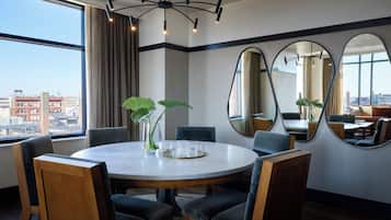 Uma sala de jantar moderna com mesa redonda, cadeiras e espelhos grandes nas paredes.