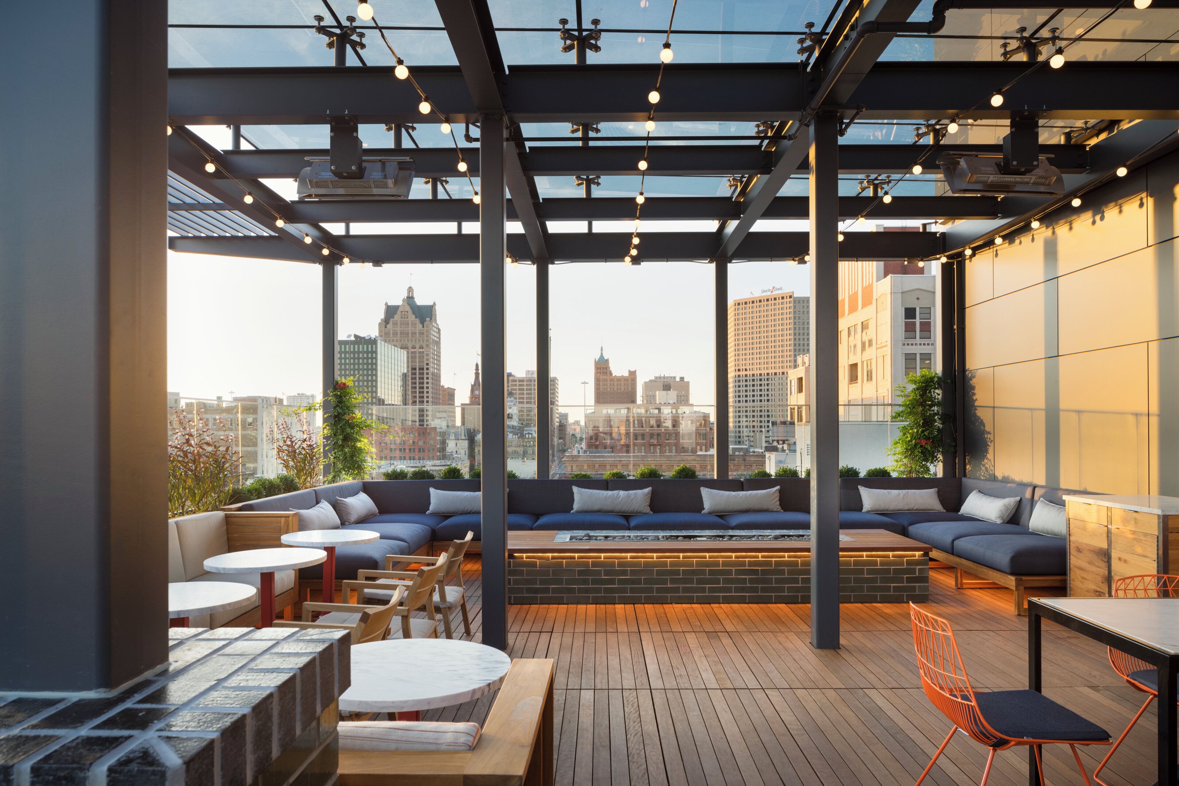 A rooftop terrace with a city view, seating areas, and tables.