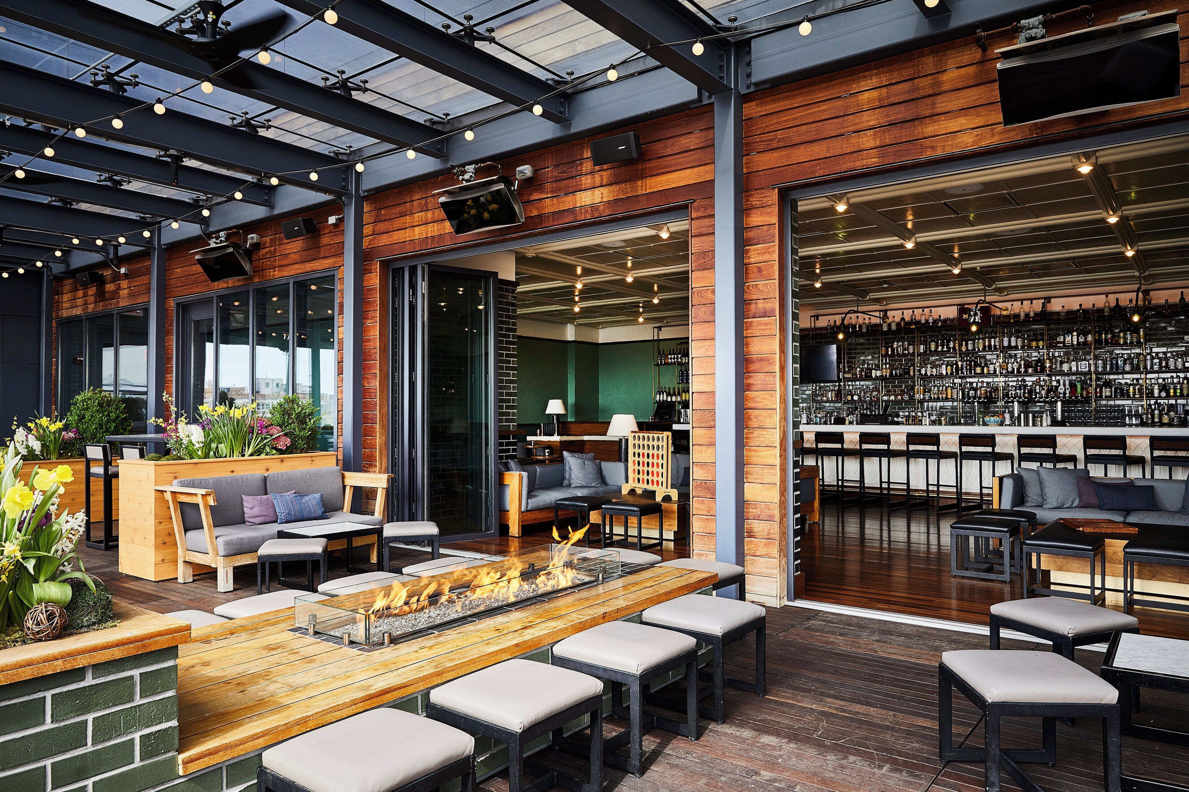 An indoor bar area with seating, a fire feature, and a bar stocked with bottles.