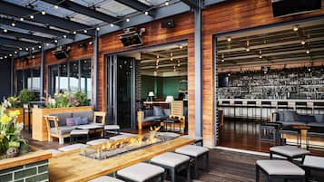 An indoor bar area with seating, a fire feature, and a bar stocked with bottles.
