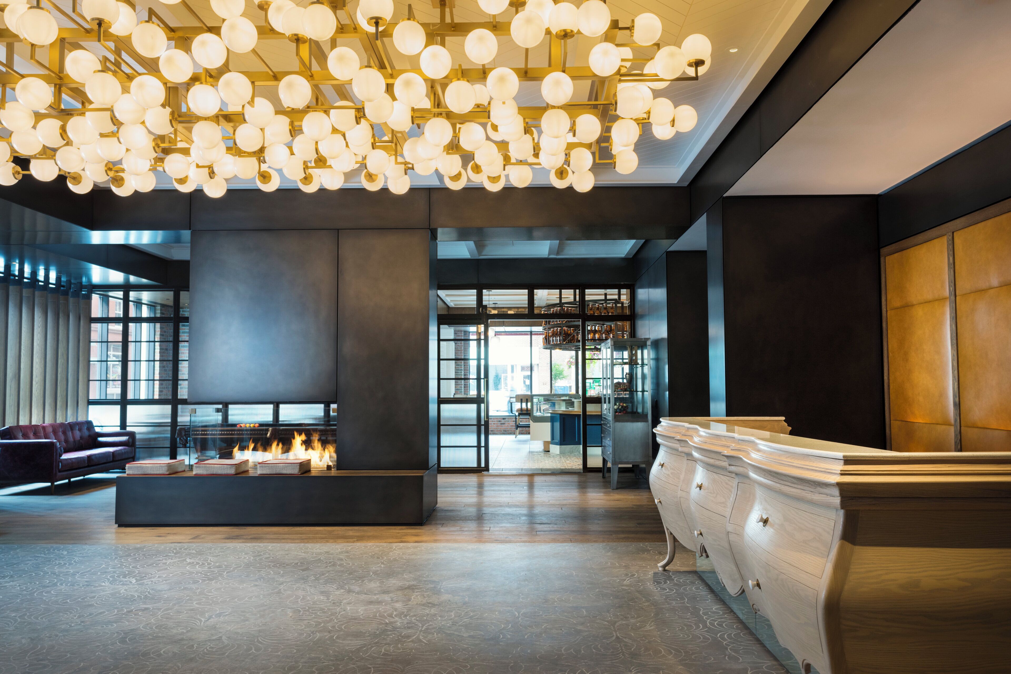 A modern lobby with a fireplace, seating area, and a reception desk.