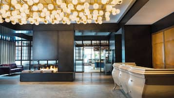 A modern lobby with a fireplace, seating area, and a reception desk.