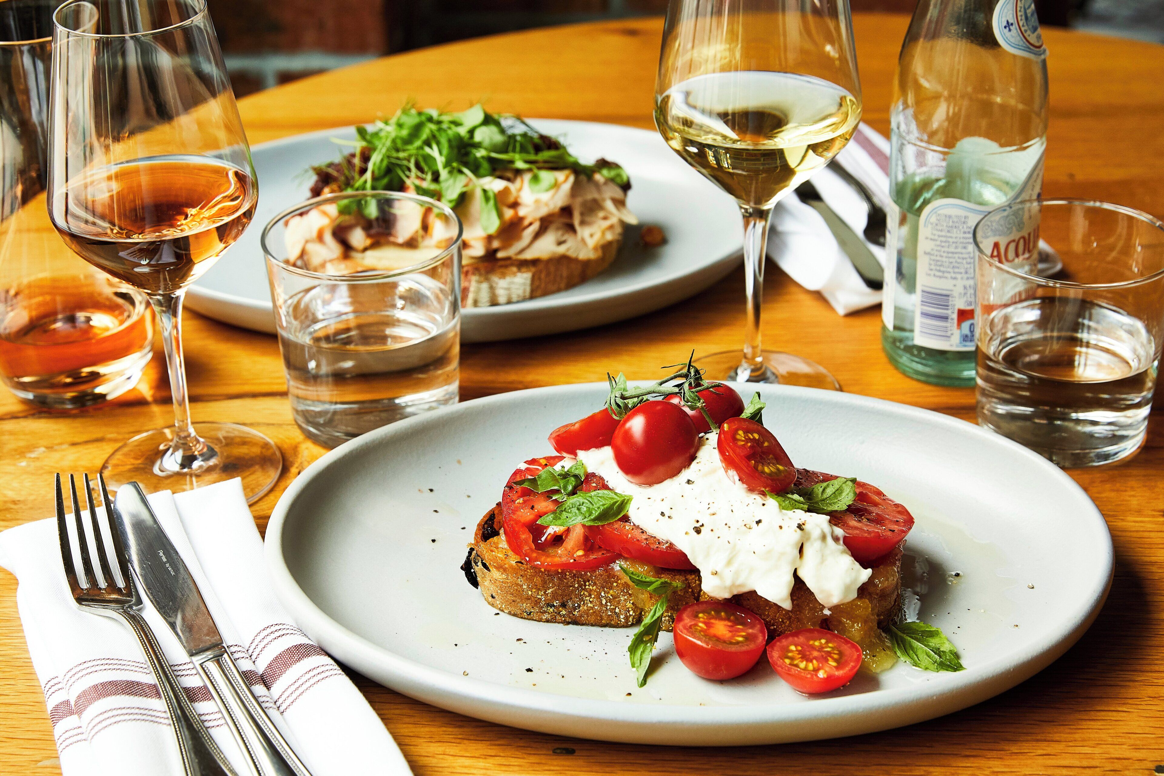 A dining table with plates of food, glasses of wine, and cutlery.