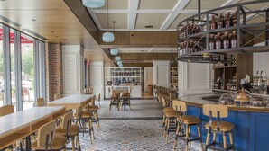 A restaurant with a bar area, wooden tables, and chairs. - Kimpton Journeyman Hotel by IHG (Milwaukee)