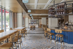 A restaurant with a bar area, wooden tables, and chairs. - Kimpton Journeyman Hotel by IHG (Milwaukee)