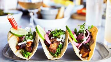 Drie taco's met diverse toppings op een metalen schaal.