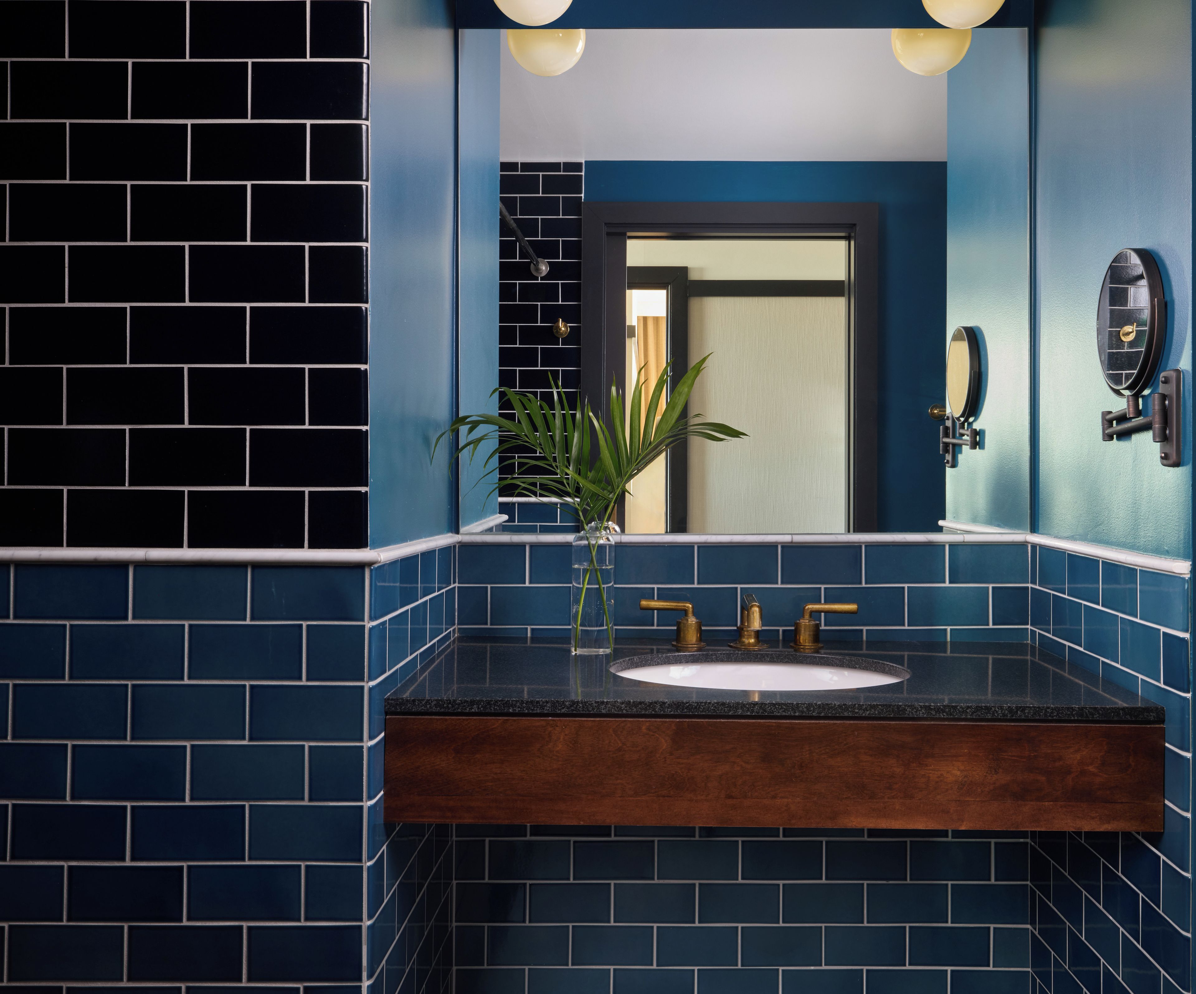 A bathroom with a sink, mirror, and a potted plant.