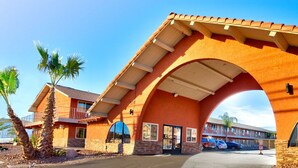 A hotel with a distinctive arched entrance, a large glass window, and a parking lot with several cars. - Hotel Galaxy (Las Vegas)
