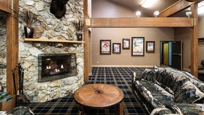 A spacious room with a stone fireplace, a plaid-patterned sofa, and a mounted moose head.