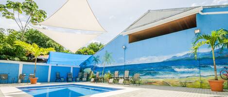 A swimming pool area with lounge chairs and a mural of a beach scene.