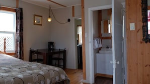 A bedroom with a bed, a desk, and a bathroom. - Jeddore Lodge Cabins (Head of Jeddore)