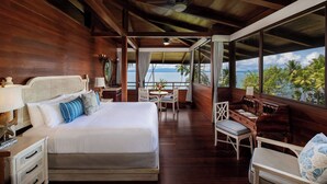 A spacious room with a large bed, a piano, and a view of the ocean. - Playa Cativo Lodge (Golfito)