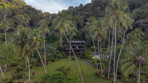 A two-story building surrounded by lush greenery and palm trees. - Playa Cativo Lodge (Golfito)