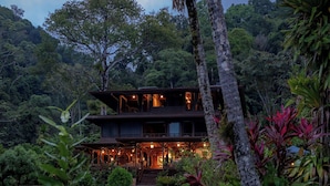 A two-story building with a covered outdoor area, surrounded by lush greenery and trees. - Playa Cativo Lodge (Golfito)