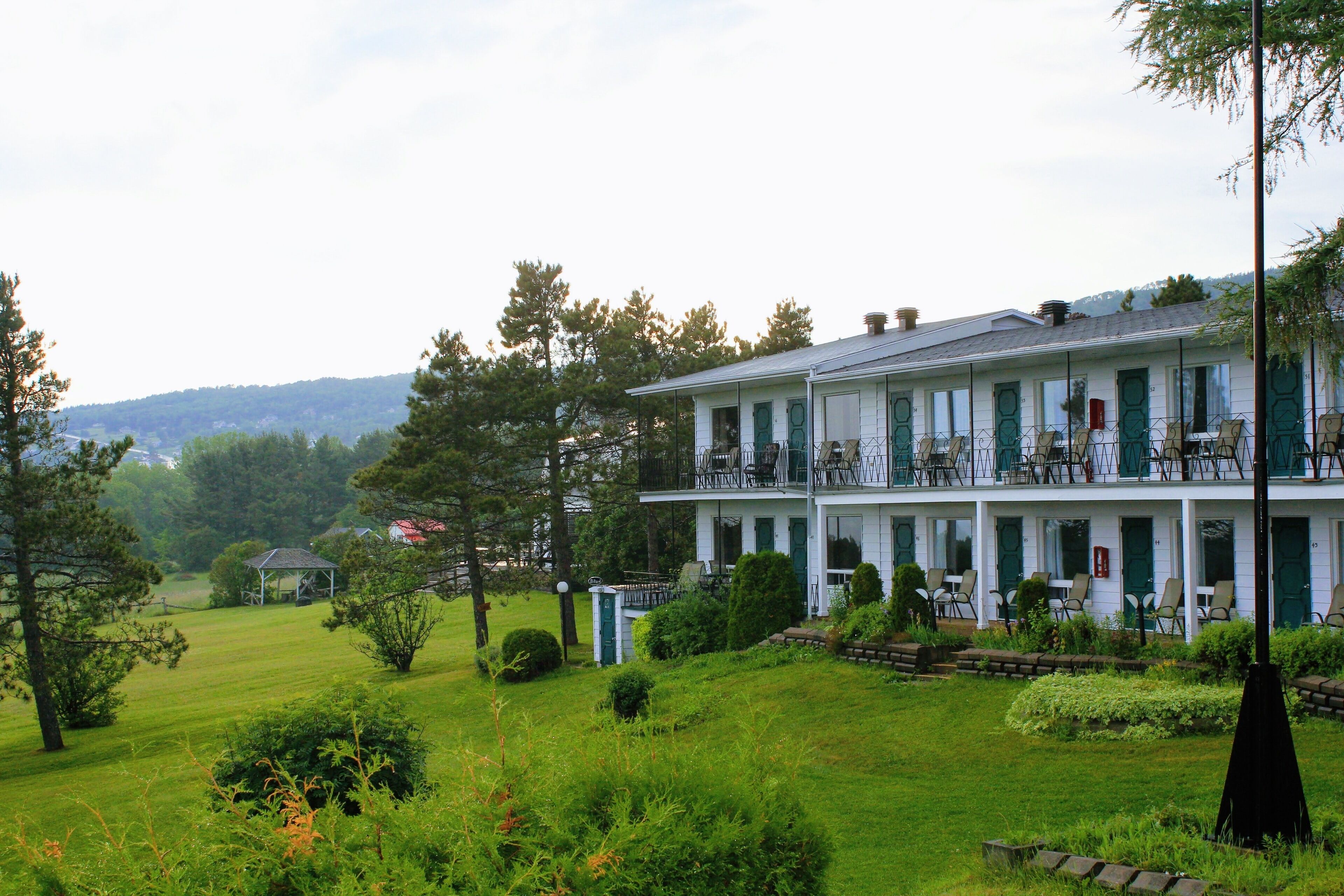 A two-story building with a balcony, surrounded by a well-maintained lawn and trees.