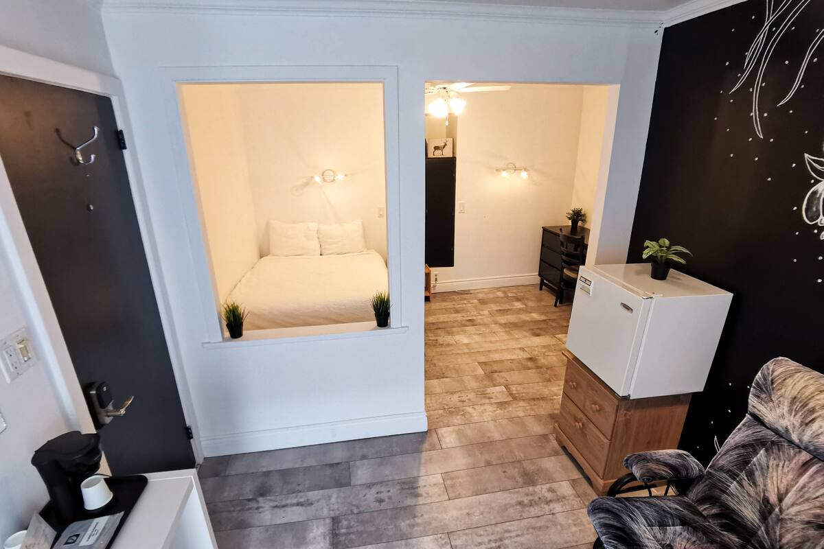 Ein gemütlicher, kompakter Wohnraum mit Bett, kleiner Küchenzeile, Sitzecke und dekorativer Wand.