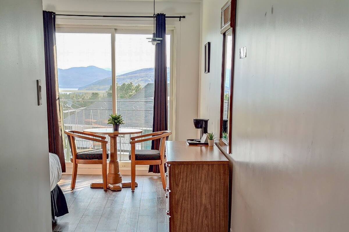 Ein Hotelgang mit Holzboden, einem Essbereich mit Tisch und Stühlen sowie Bergblick durch große Fenster.