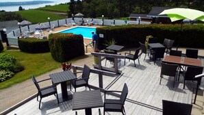 A poolside area with outdoor seating and a view of the lake. - Auberge de Nos Aïeux (Les Eboulements)