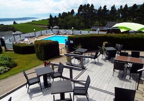 Zona junto a la piscina con mobiliario exterior y vistas al lago.