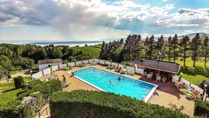 A swimming pool with a view of the sea, surrounded by a white fence, and a building with a tiled roof. - Auberge de Nos Aïeux (Les Eboulements)