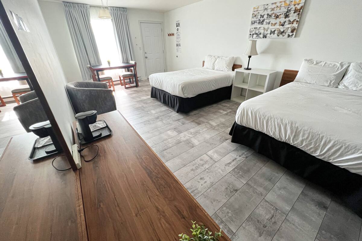 Ein Hotelzimmer mit zwei Betten, einem Schreibtisch, einem Stuhl und einem kleinen Tisch.
