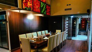 Un comedor moderno con una mesa de madera alargada, sillas blancas y una pared decorada con fruta vibrante.