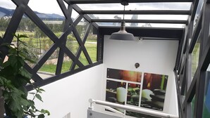 Un interior moderno con techo de vidrio, una puerta blanca y vistas a un paisaje verde.