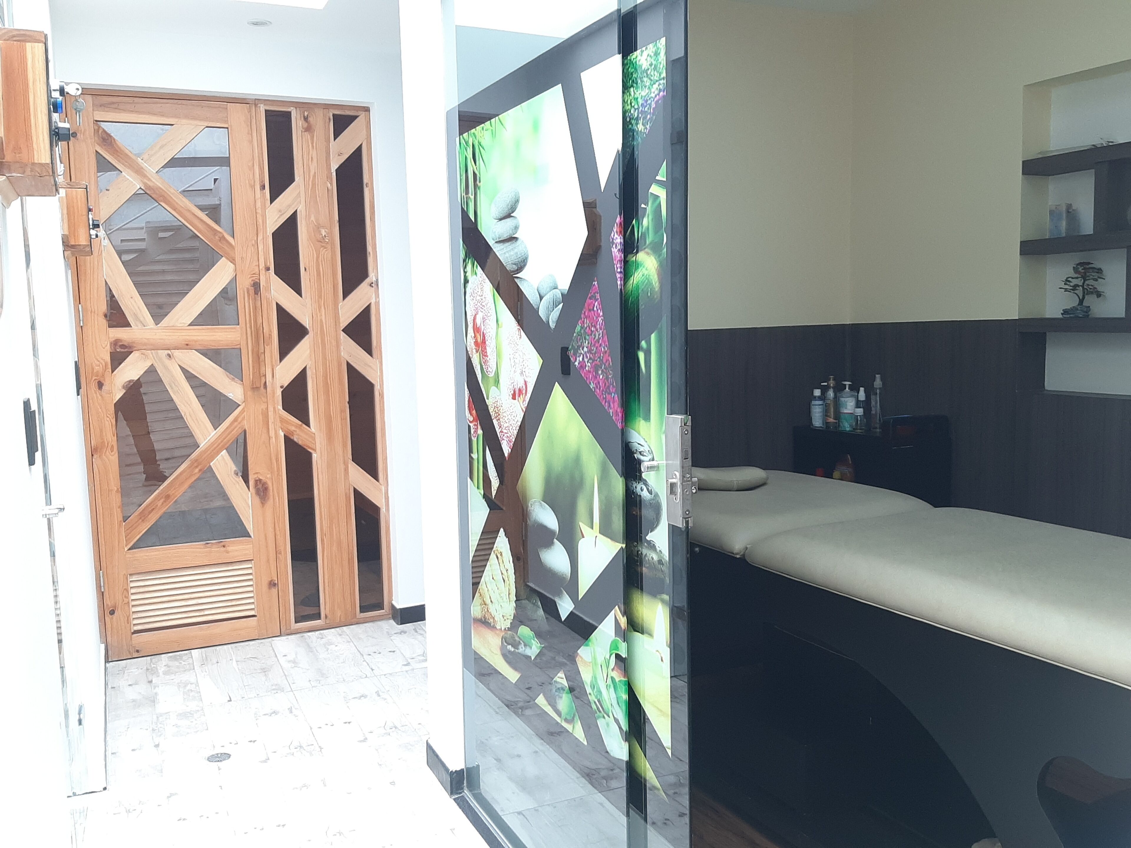 Una habitación con cama, puerta de madera y separador de vidrio con diseño decorativo.