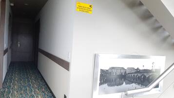 A hallway with patterned carpet, a door at the end, and a framed picture on the wall.