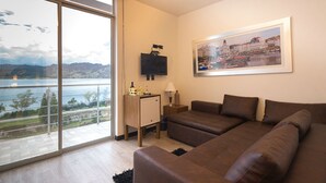 Una sala de estar moderna con un ventanal grande, un televisor de pantalla plana y un cuadro con vistas a la ciudad.