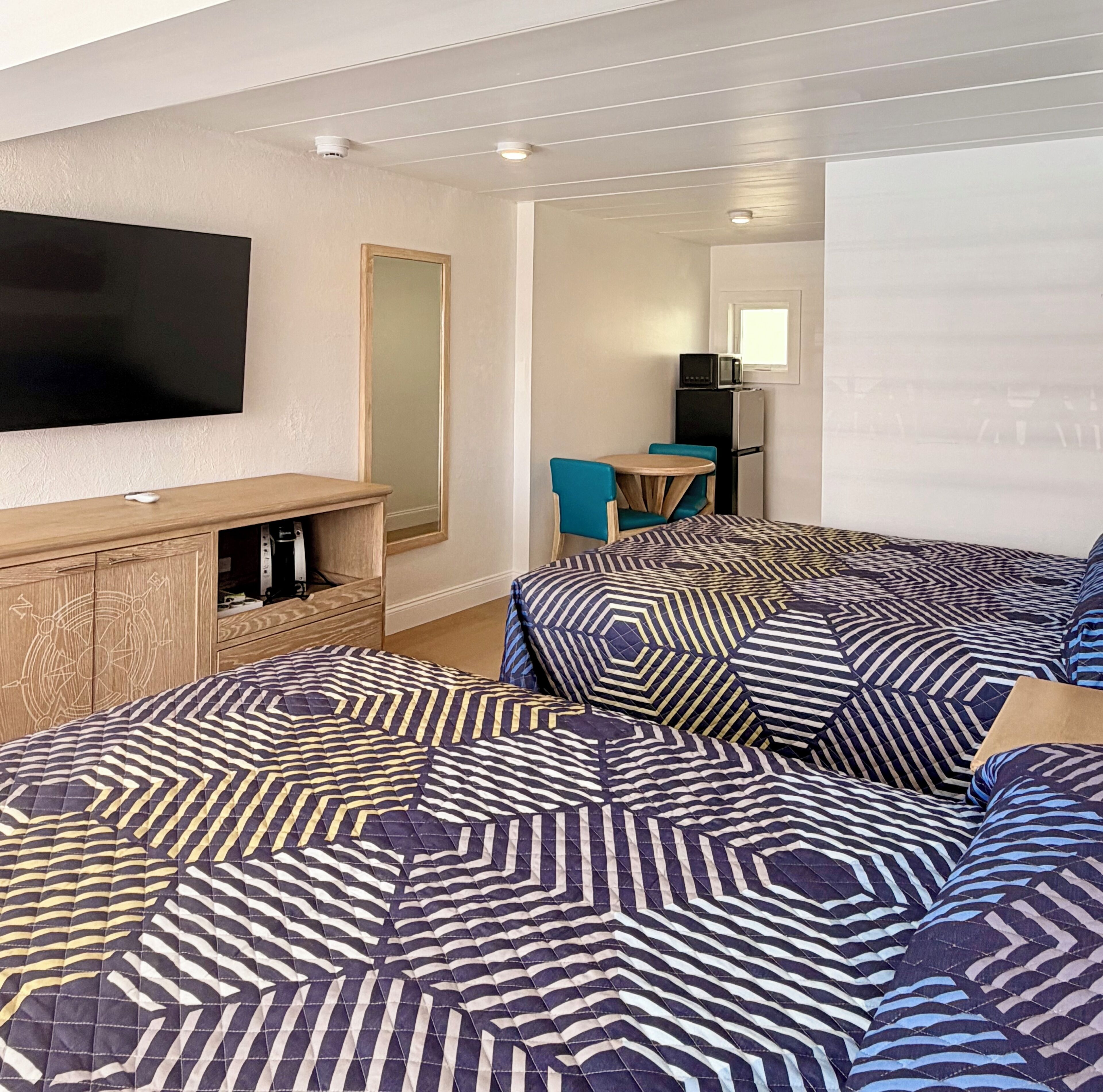 A hotel room with a large bed, a television, a small table, and a refrigerator.