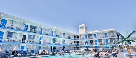 A hotel with a pool area, multiple balconies, and a sign indicating a restaurant.