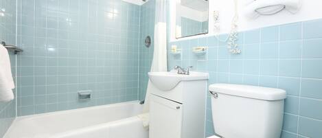 A bathroom with a bathtub, toilet, sink, and blue tiled walls.