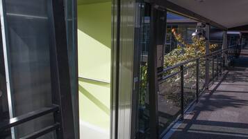 A modern building with large glass doors, a metal railing, and a pathway leading to a staircase.