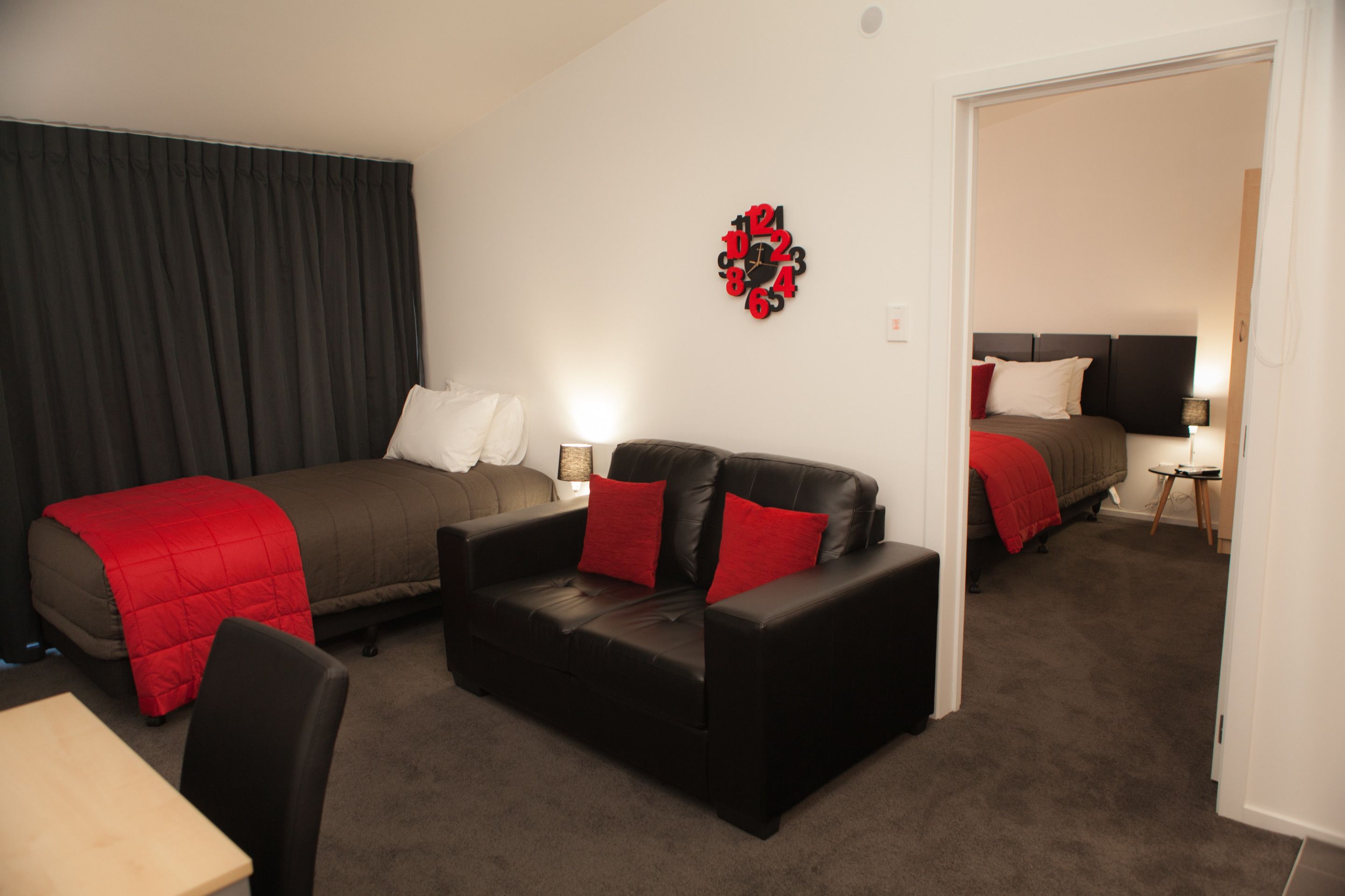 Una habitación de hotel con cama, sofá, escritorio y un reloj de pared.