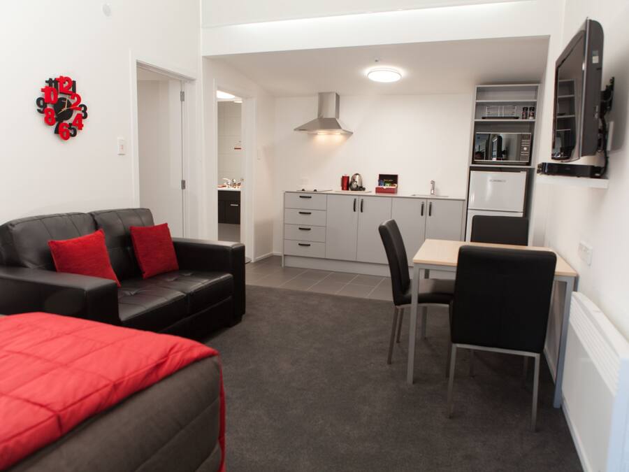 A compact living space with a sofa, a dining table, and a kitchenette.