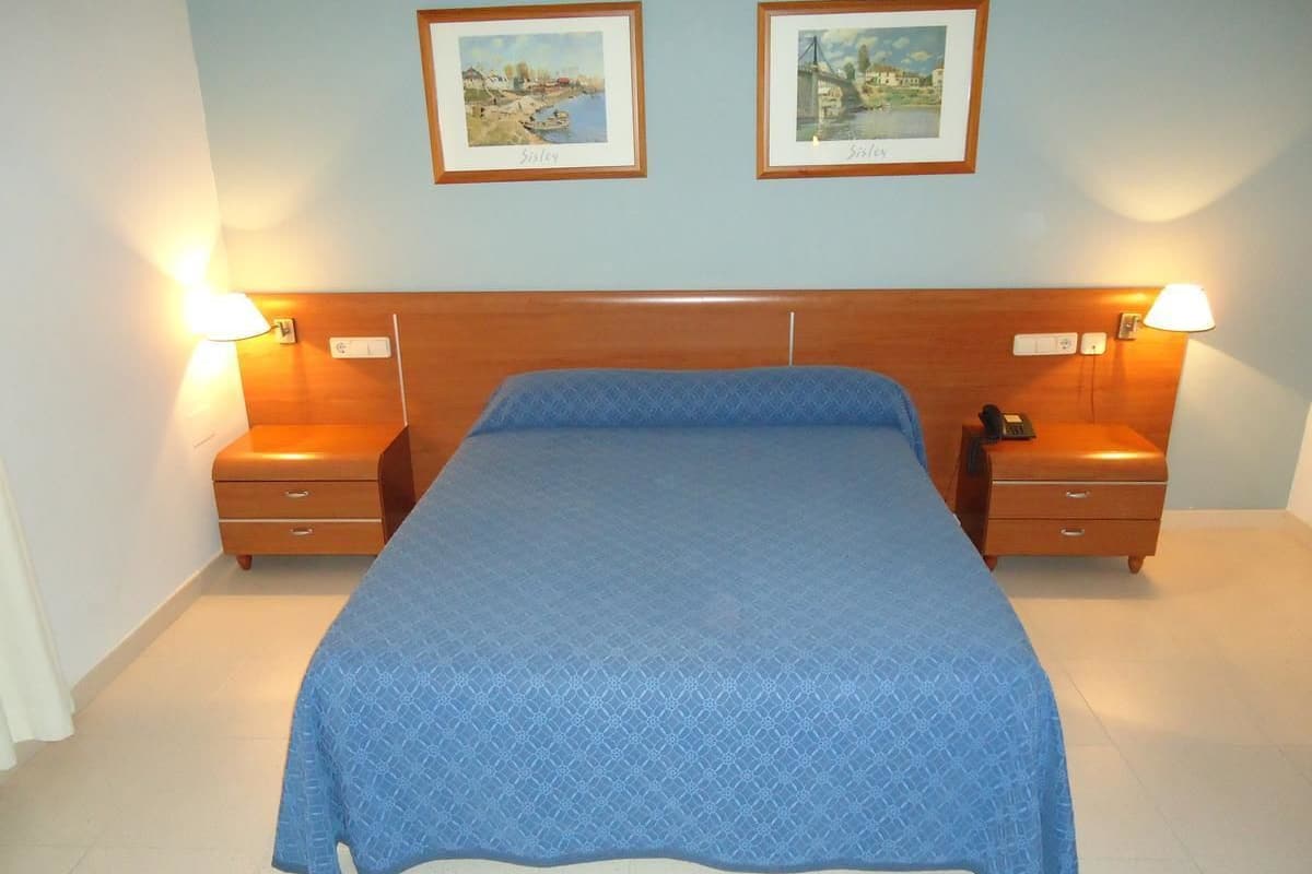 Een slaapkamer met een groot bed, twee nachtkastjes en twee wandlampen.
