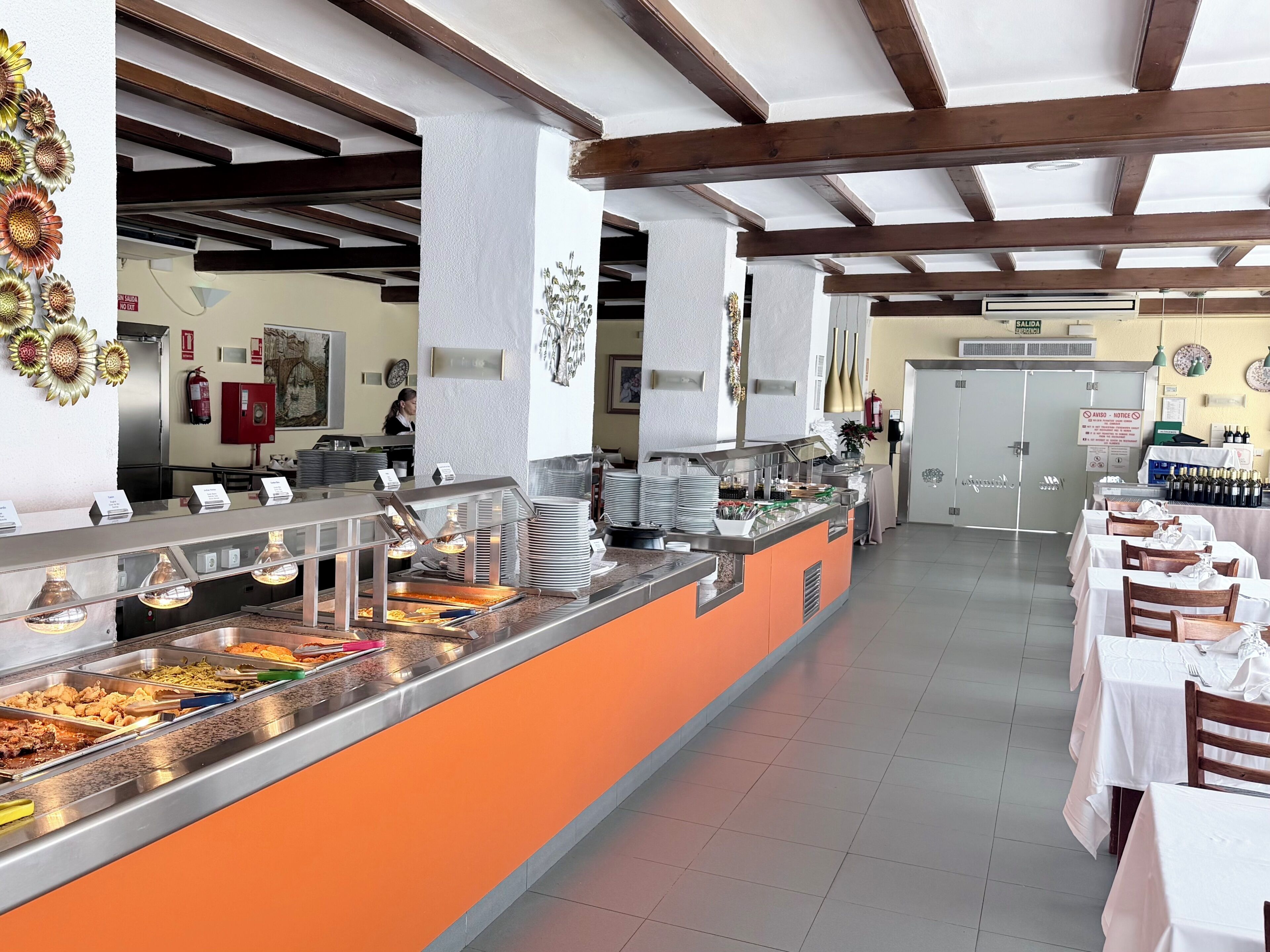 Ein Bereich mit Buffet, Speiseausgaben, einer Theke und Tischen mit Stühlen.
