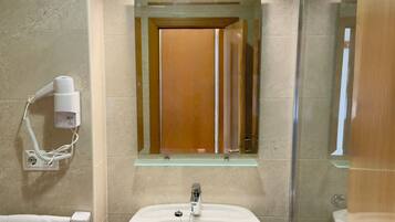 A bathroom with a white sink, a mirror, a hairdryer, and a towel rack.