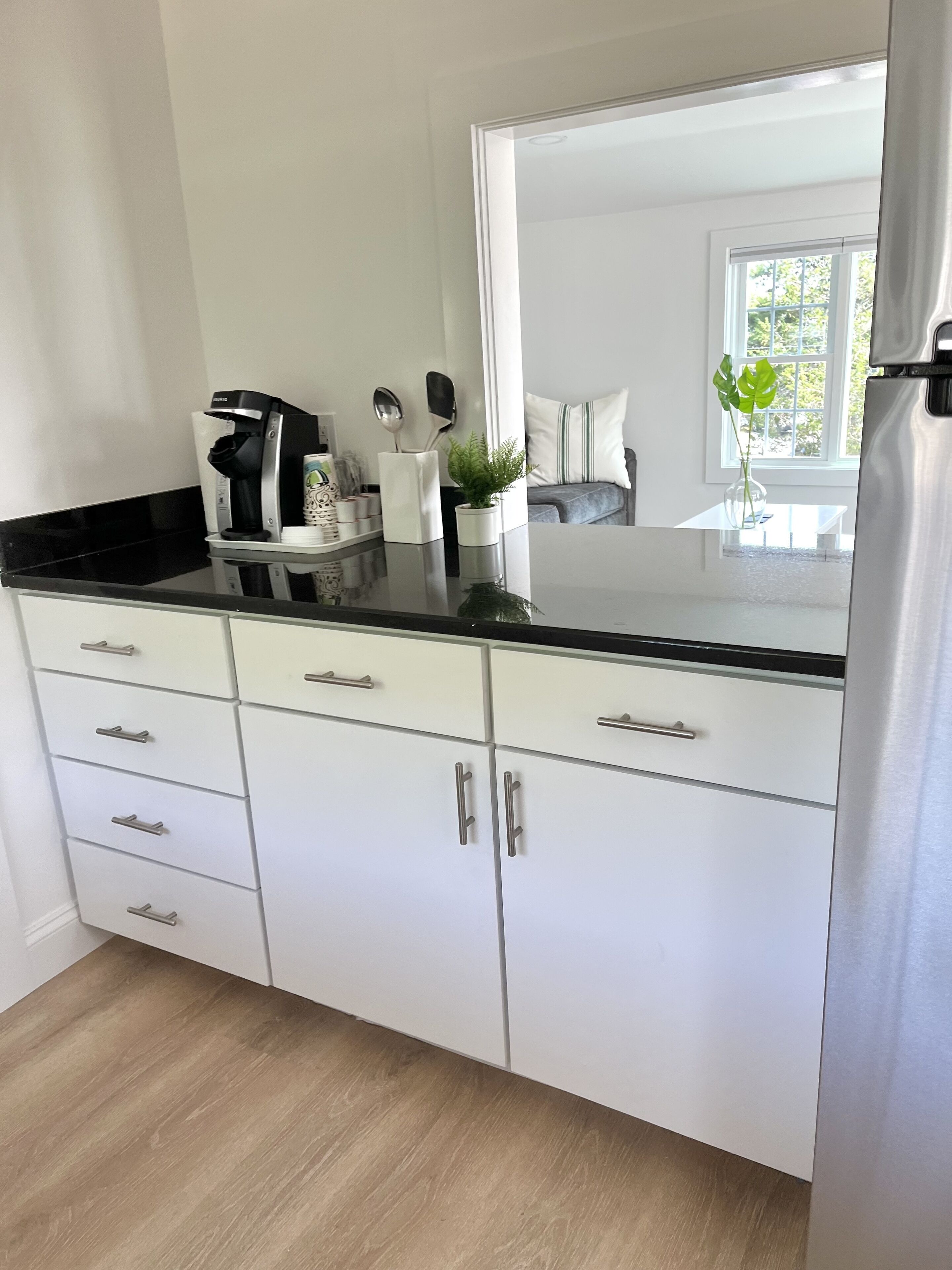 Een moderne keuken met witte kastjes, een zwart aanrecht en roestvrijstalen apparatuur.