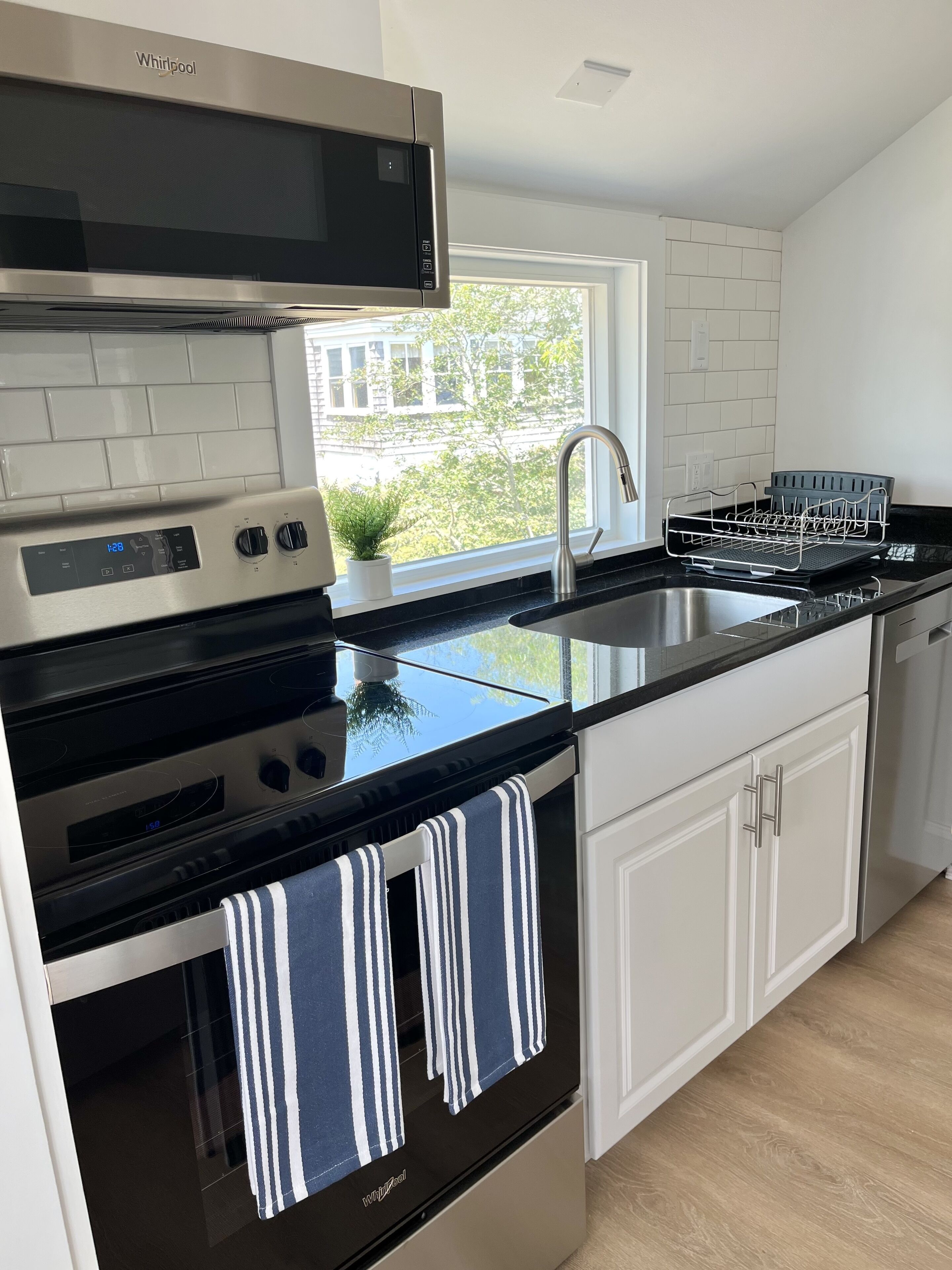 Una cocina moderna con un extractor de acero inoxidable, horno empotrado, un lavamanos doble y una ventana con vistas al exterior.
