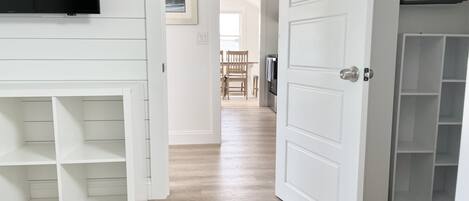 A hallway with a TV mounted on the wall, a wooden door, and a closet with shelves.