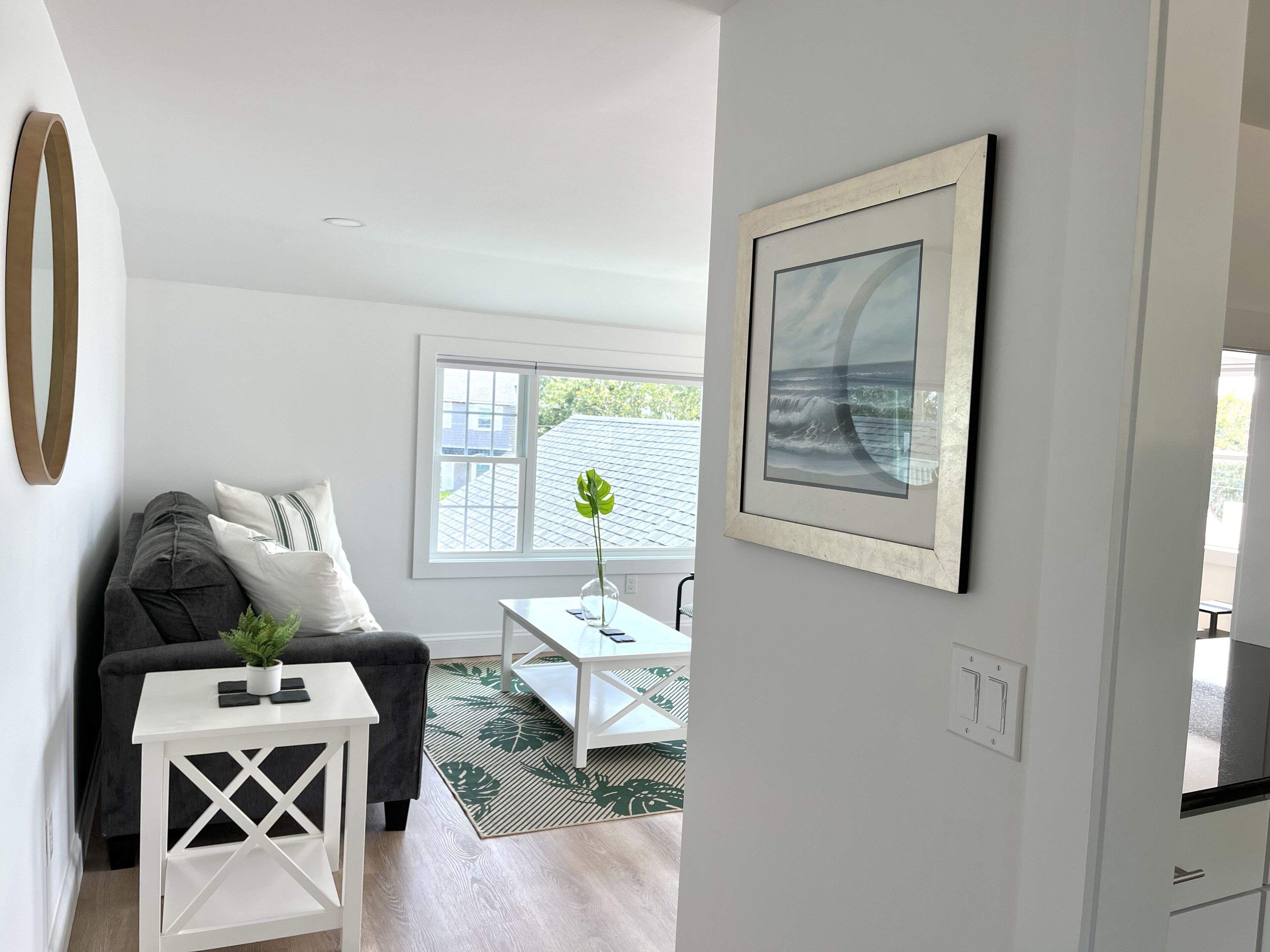 A modern living room with a grey sofa, a white coffee table, and a framed picture on the wall.