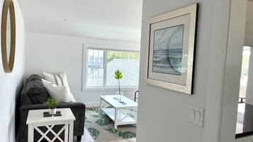 A modern living room with a grey sofa, a white coffee table, and a framed picture on the wall.