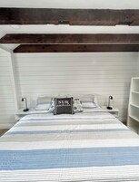 A bedroom with a bed, two bedside tables, a nightstand, and a built-in shelving unit.